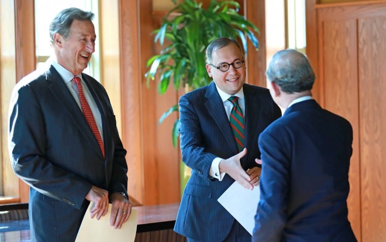 Andrew D. Martin shakes hands with Mark S. Wrighton as Craig Schnuck looks on